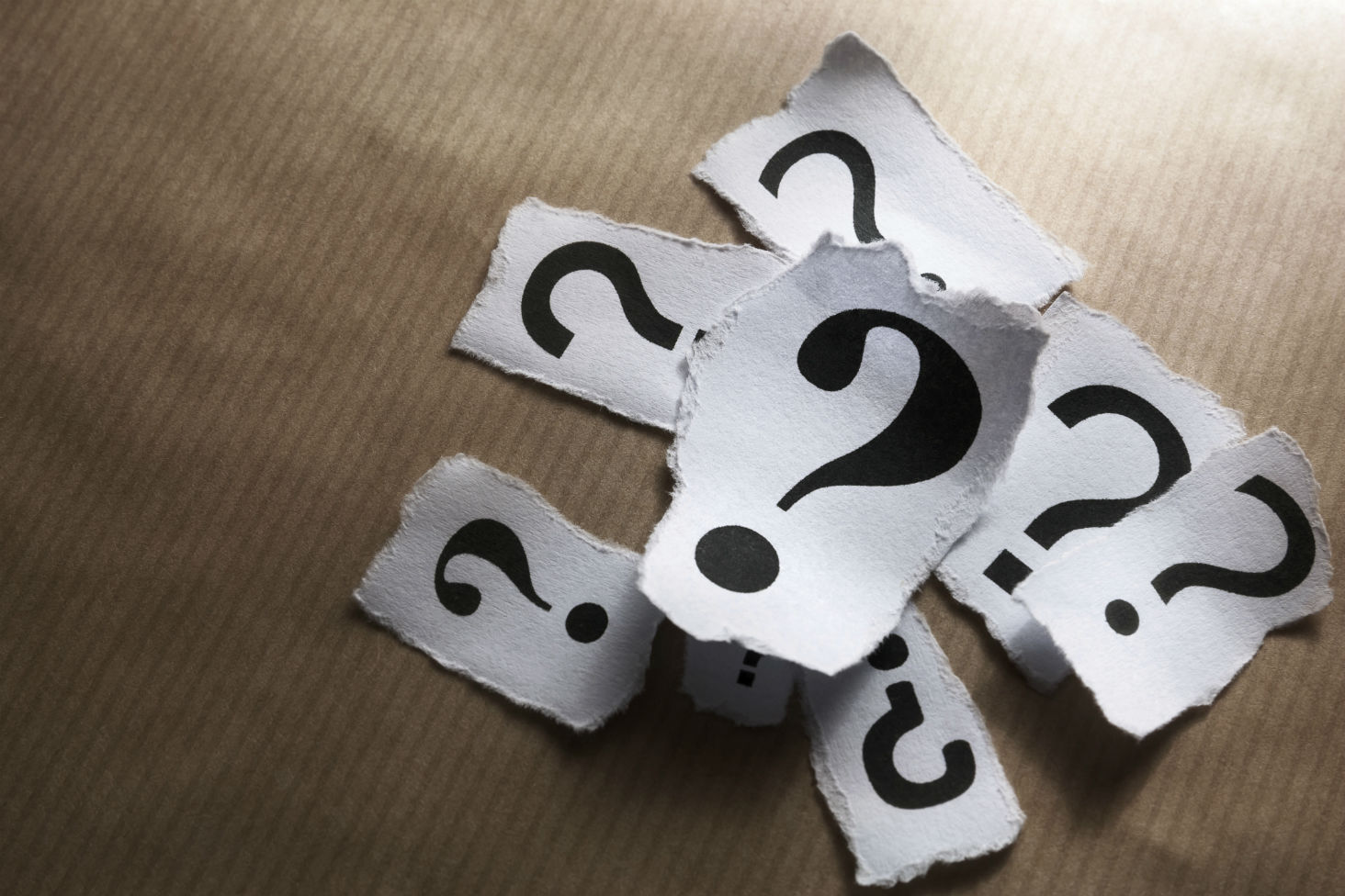 An image showing a pile of pieces of paper with question marks on them