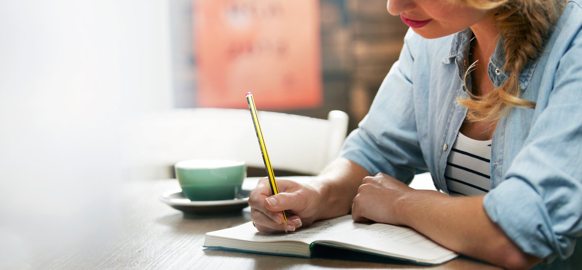 An image of someone sitting at a desk with a notepad and pencil